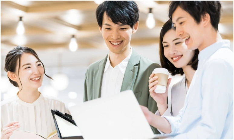 ラップトップPCを囲んで笑顔で相談している仲間たち